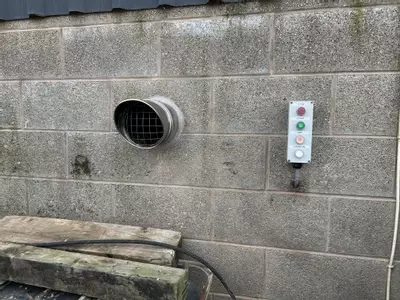 External chimney flue outlet and remote control panel installed for operating a hot water pressure washer from outside the building at a Twycross farm.